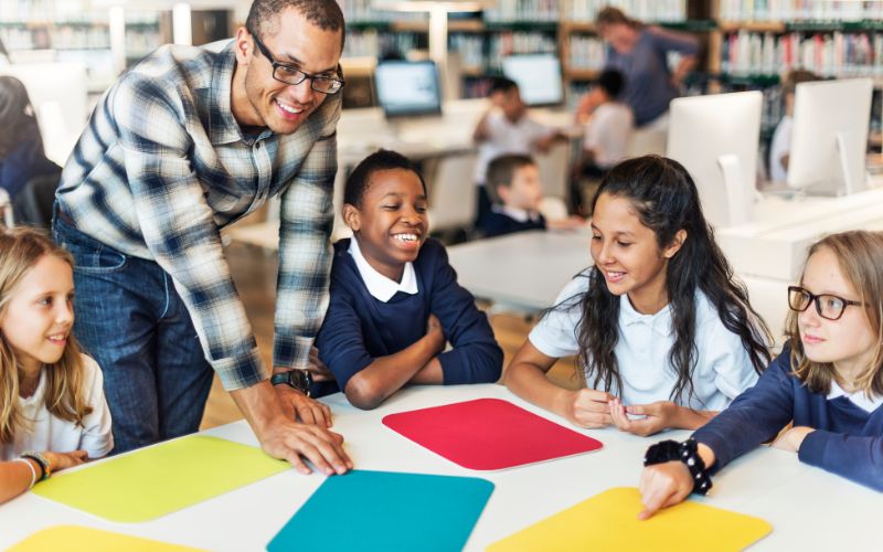 Teaching assistant laughing with a group of students who are doing group work